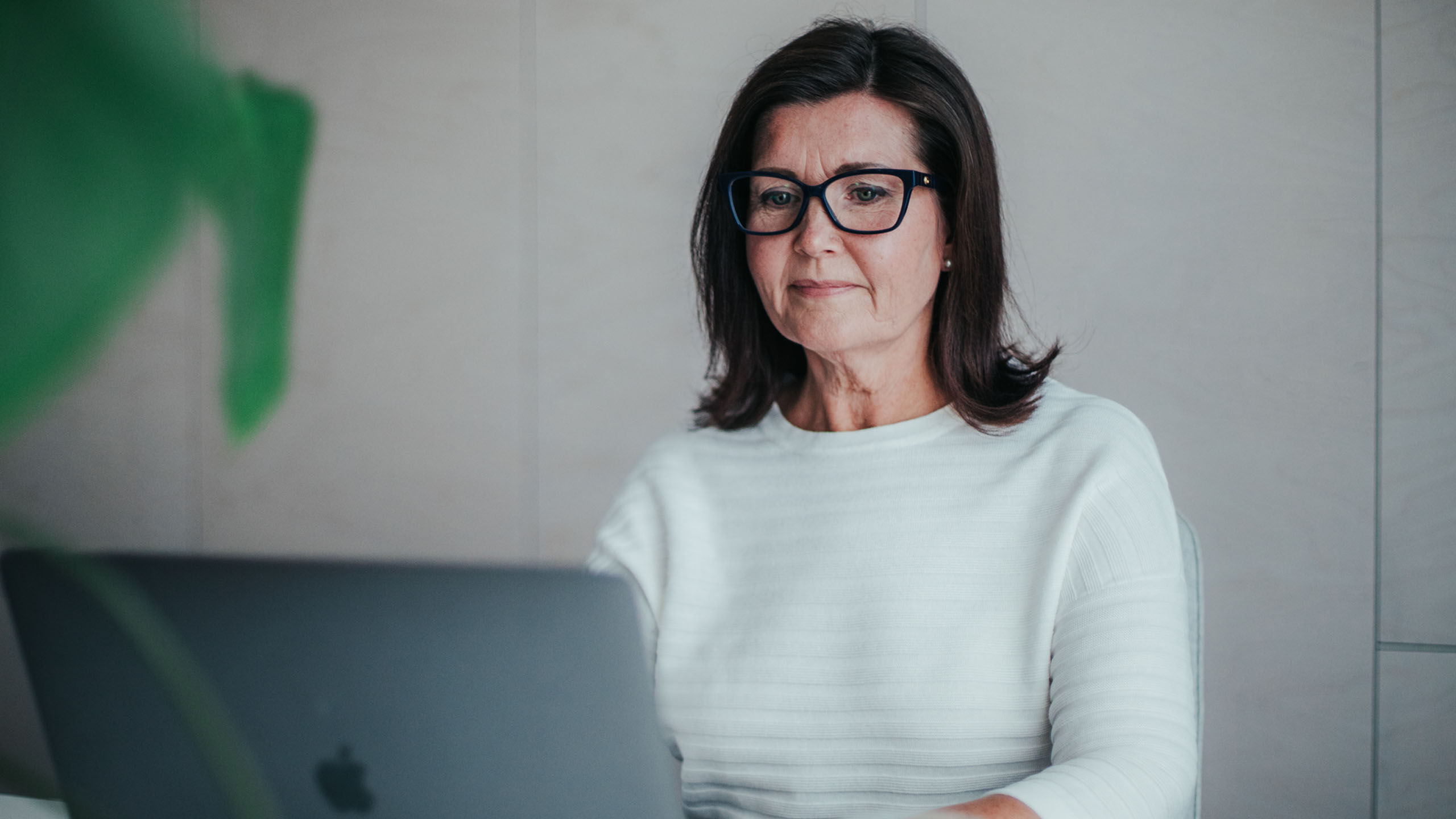 Nainen tietokoneella silmälasit päässä